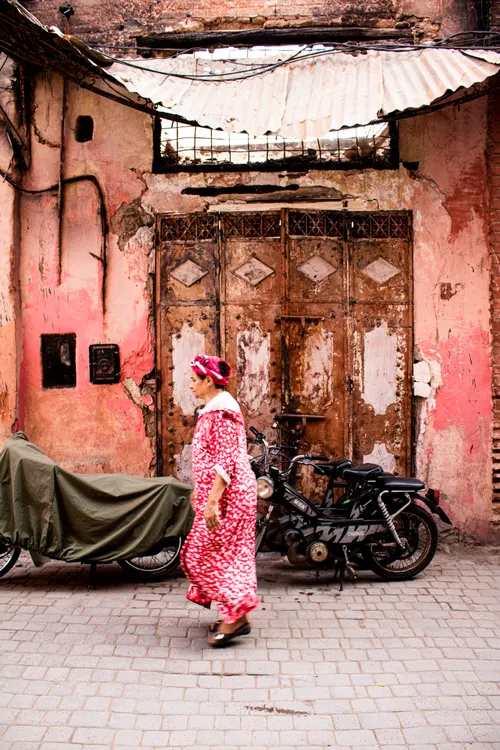 Vrouw in roze djellaba in een straatje in Marrakech